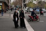 Women cross an intersection in downtown Tehran, Iran, Thursday.
