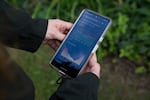 This photo shows a smartphone that's held in the hands of Kasey Hatch. Its screen shows two graphs that display the levels of noise measured in the area near the Vantage data center in Sterling.
