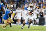 Washington quarterback Demond Williams Jr. runs with the ball past UCLA defensive back Scooter Jackson during the first half of an NCAA college football game, Saturday, Nov. 22, 2025, in Pasadena, Calif.