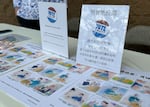 Judy Lee stands behind a voter registration booth organized by the Chinese American Citizens Alliance outside of 99 Ranch Market in Beaverton, Ore., on Sept. 15, 2024. Tommy Ly's comic strips are displayed on the booth table.