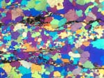 A thin, polished slice of a rock collected from the Jack Hills of Western Australia, viewed through a special microscope equipped with a gypsum plate that shows the rainbow spectrum of quartz that makes up the rock. Whereas the rocks at the Jack Hills are greater than 99% quartz, the remaining 1% of material includes the precious zircons.