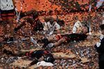 Three Oregon State men's basketball players lay on a confetti-covered court in celebration.