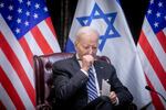A man pauses while sitting in front of American and Israeli flags.