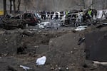 Residents stand near their apartment building, damaged during a Russian missile strike in Ukraine's capital Kyiv. Dozens were injured during the early hours of Dec. 13 after air defense systems intercepted incoming Russian ballistic targets.