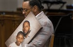 Antonio Mays Sr. holds a portrait of himself and his son.