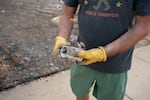 Resident TJ Brill displays a cup he is able to pull from the rubble of his home on Thursday. The cup sat next family heirlooms, including World War II medals, he hopes to find.