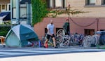 A man walks in the street to bypass the tents and debris sitting on the sidewalk on SW 12th Avenue in Portland, June 24, 2021. 