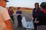 Oregon Zoo area supervisor Jen Osburn Eliot, center, holds up a container of frogs next to a cooler, Aug. 6, 2024. The frogs were kept in the cooler during the car ride to maintain stable temperatures.