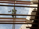 A worker, pictured July 5, 2022, on a skylight of the nine-acre wooden roof that will cover the expanded main terminal at Portland International Airport. Crews should start moving the roof, piece by piece, in September.