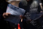 A woman holds a sample ballot on the second day of early voting at a polling station, Oct. 18, in Fairview, North Carolina. Despite concerns about early voting access after Hurricane Helene, many local officials reported record turnout for early voting, like in nearby Yancey County.