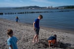 Children visiting with family from Texas play on Dibblee Beach in Rainier, Ore., across the river from the Nippon Dynawave Packaging Co., seen in the background. After reading about the accident and river contamination, they did not allow the children to play in the water.