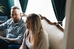 Ben Brewington looks at his wife, Sarah Brewington, while they sit on a couch in their living room.