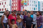 In this photo provided by Michelle Angela Ortiz, Ortiz, left, stands next to the Cully residents she depicted in her mural, "Together We Bloom," at Last Adelitas in Northeast Portland.