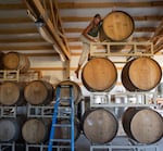 Bethany Kimmel, 41, tops the wine barrels at her home in White Salmon, Wash., on July 14, 2026. Kimmel is the owner of Soča Wine Shop & Bar and is currently making wine with the grapes of other growers while waiting for her vines to reach maturity.