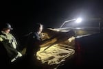 OSP Senior Trooper Martin Maher (left) and Sgt. Leland Farrar (center) put a decoy deer into the back of their vehicle, following a predawn operation to catch poachers. The pair were working near some off-roads by Dexter, Ore., after a series of calls were made about suspected poacher activity.