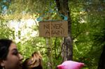 People hold a sign attached to a plastic clothes hanger that reads "never again."