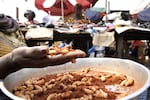 A vendor holds big weevil larvae at Kinshasa's Gambela market. At Gambela market, people can find insects for all tastes : big weevil larvae leaving a smoothness feeling in the mouth, slightly crunchy caterpillars or termites cracking between your teeth