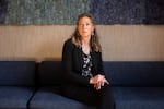 Noella Sudbury is the founder of Rasa Legal, a non-profit that uses technology to help people expunge their criminal records. She is sitting on a couch with her hands in her lap. Sudbury has long, curly hair and she is wearing a dark suit and a dark floral top.
