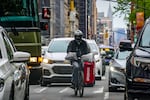 FILE - A food delivery worker rides through the a busy street in lower Manhattan, Friday, April 28, 2023, in New York.