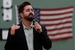 Cory Bowman preaches in a gymnasium against an American flag.
