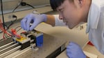 University of Washington Ph.D. candidate Youngshang Han sets up a test that will determine how far his device can stretch before losing conductivity.