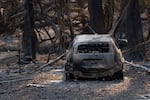 A burned car sits near a house that was destroyed by the fire.