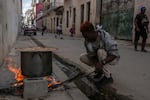 A man cooks soup over an open fire on a sidewalk, during a blackout in Havana, Cuba, on Wednesday.