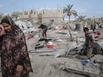 Palestinians look at the destruction following an Israeli airstrike in al-Muwasi, a designated humanitarian zone in Khan Younis, southern Gaza, on Tuesday. The Israeli military said it was targeting a Hamas command and control center and killed three Hamas commanders in the strike. Hamas did not confirm the deaths.