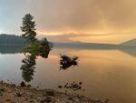 The sun casts a yellow glow on Waldo Lake as it shines through smoke from the Cedar Creek Fire.