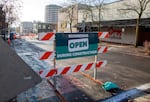 A sign with the words "businesses open during construction" in the middle of a city street.
