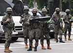South Korean soldiers stand in the street wearing masks that cover the lower part of their faces.