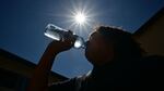 A child sips water from a bottle under a scorching sun on Tuesday in Los Angeles. Forecasters say temperatures  could reach as high as 112 degrees in the densely populated Los Angeles suburbs in the next week as a heat dome settles in over parts of California, Nevada and Arizona.