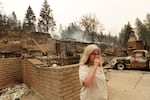 Kimberley Sather stands at the duplex she rents on W. Indian Trail Rd. after it burned in a wildfire in Spokane, Wash., Sunday, Aug. 2, 2026.