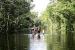 Dustin Holmes, second from right, holds hands with his girlfriend, Hailey Morgan, while returning to their flooded home with her children Aria Skye Hall, 7, right, and Kyle Ross, 4, in the aftermath of Hurricane Helene, Friday, Sept. 27, 2024, in Crystal River, Fla.