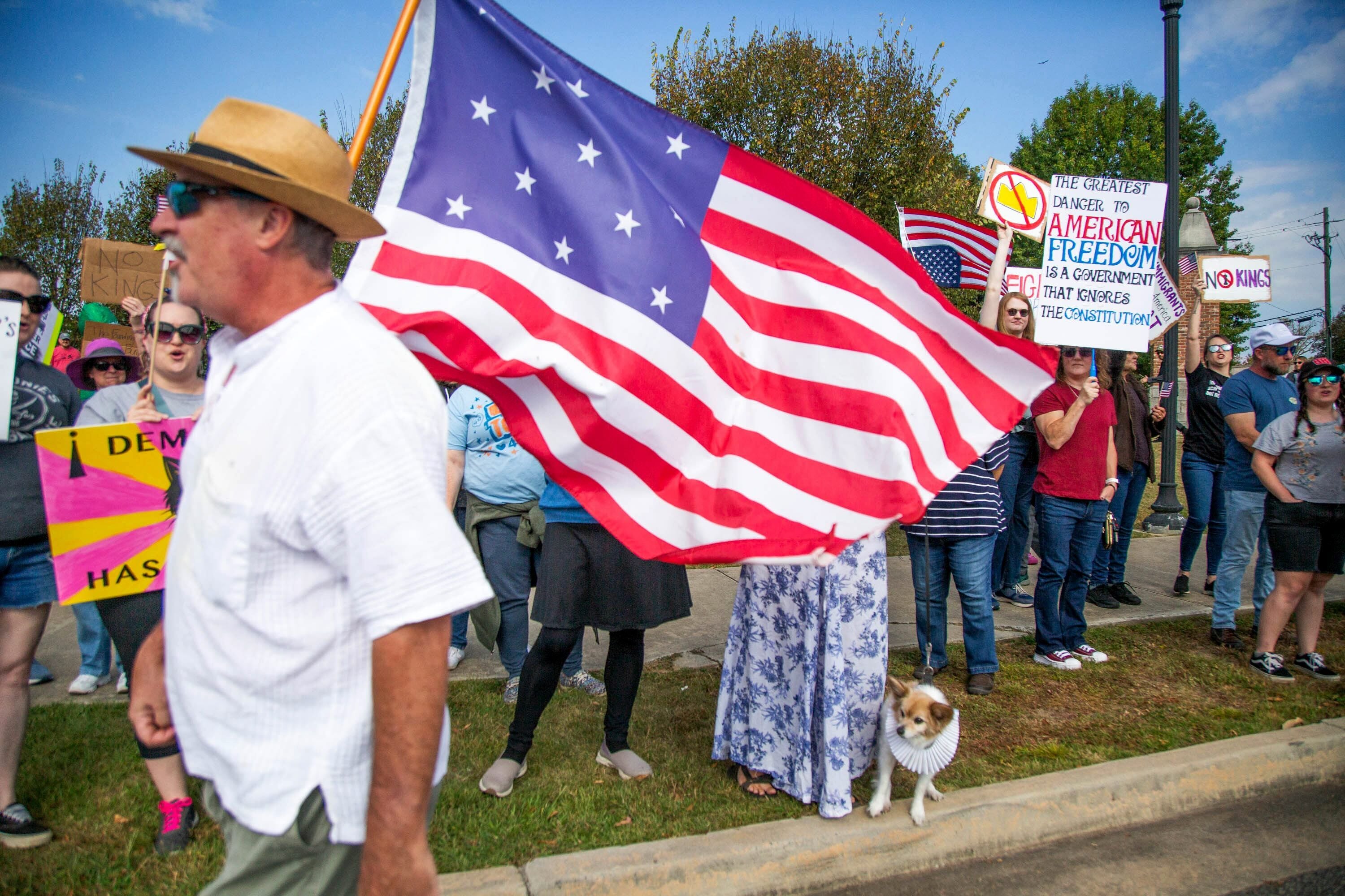Joe Bondulich carries a flag past the crowd gathered on the side of College Street in Macon, GA.