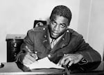 Jackie Robinson is shown in military uniform signing a contract with a farm team for the Brooklyn Dodgers.