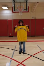In this provided photo taken in January 2026 at the Multnomah Athletic Club in Portland, Quinn Brown poses with a warm-up jacket worn by basketball legend Wilt Chamberlain during the 1972 NBA Finals. The jacket, which Brown found and bought for $3 at the Goodwill store in Hillsboro, is expected to fetch as much as $250,000 at auction.