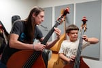 Tyler DeBolt, left, gives Drax Brown, 9, his first lesson on the double bass at the Albany Youth Orchestra in Albany, Ore. on Oct. 8, 2026.
