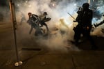 Protesters scramble to get away from approaching police firing tear gas and impact munitions to disperse protesters in downtown Portland during 4th of July demonstrations against systemic racism and police violence.