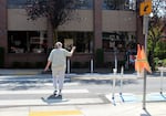 A pedestrian waves to oncoming traffic while crossing Northeast Fremont Street, Sept. 1, 2025. Pedestrian safety flags have been attached to several crosswalks, like this one, to alert drivers when people are crossing.