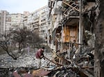 A man clears debris at a damaged residential building in Kyiv in February, just after Russia started its invasion.