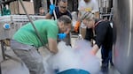 People huddled around a tub with liquid nitrogen vapors fuming around them.