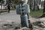A man walks past an unexploded tail section of a 300mm rocket which appear to contained cluster bombs launched from a BM-30 Smerch multiple rocket launcher embedded in the ground after shelling in Lysychansk, Lugansk region on April 11, 2022.