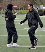 Athlete on phone faces away from the camera while other athlete smiles