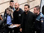 Andrew Tate (pictured third from the right) and his brother Tristan Tate (second from the right) arrive handcuffed and escorted by police at a courthouse in Bucharest on Jan. 10, 2023 for a hearing on their appeal against pre-trial detention for alleged human trafficking, rape and forming a criminal group.