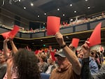 Members of the audience express dissent through red cards at the Portland Mayoral Candidate Debate.