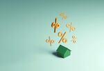 Conceptual image of a single green house with a group of gold percentage signs hovering above, could illustrate concepts around interest rate, mortgage loan and home finances