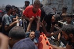 Injured Palestinians are transferred to an ambulance after being wounded while waiting for aid arriving from the northern Gaza Strip, in Gaza City, Tuesday.
