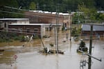 A street with several buildings is shown with brown water about three feet deep.
