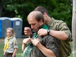 One bratchyk, or "brother" who serves as a male counselor, helps another to get his bandana straight.